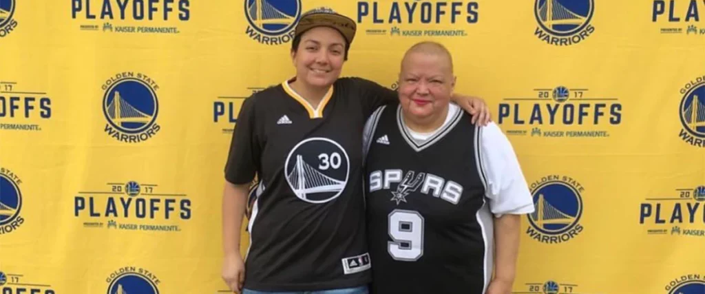 A Golden State Warriors fan hugs a Los Angeles Spurs fan as they pose for a picture during the 2017 NBA playoffs.