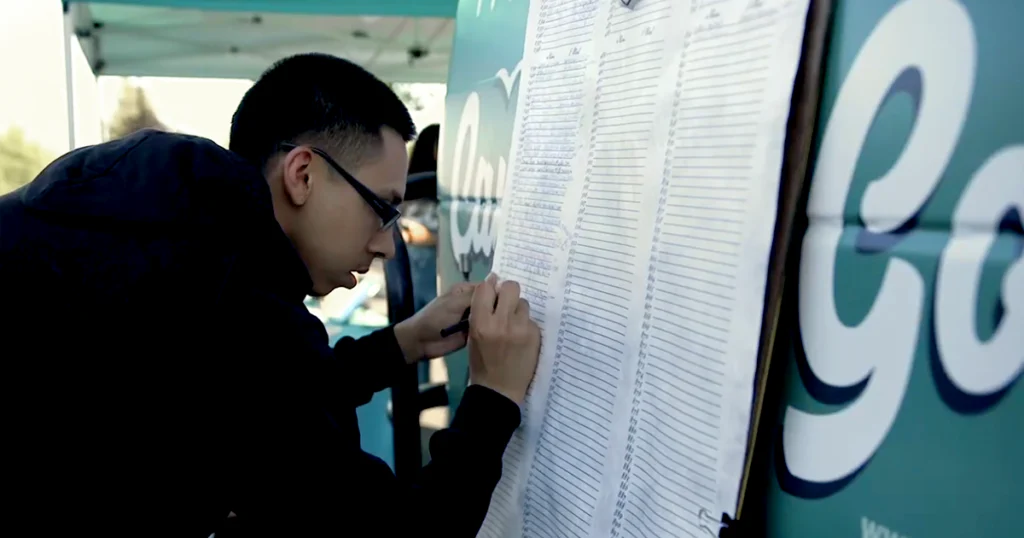 A person signs a large petition board at Jetty Extracts’ “Cannabis for Good Tour” event, supporting compassionate cannabis access and the continuation of California’s SB 34 Compassionate Care Act through the Jetty Shelter Project initiative.