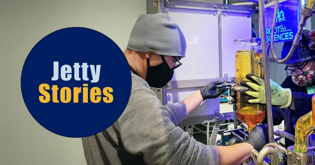 Jetty extraction team working in a lab, operating cannabis extraction equipment with protective gloves and masks, alongside a circular graphic reading “Jetty Stories.”