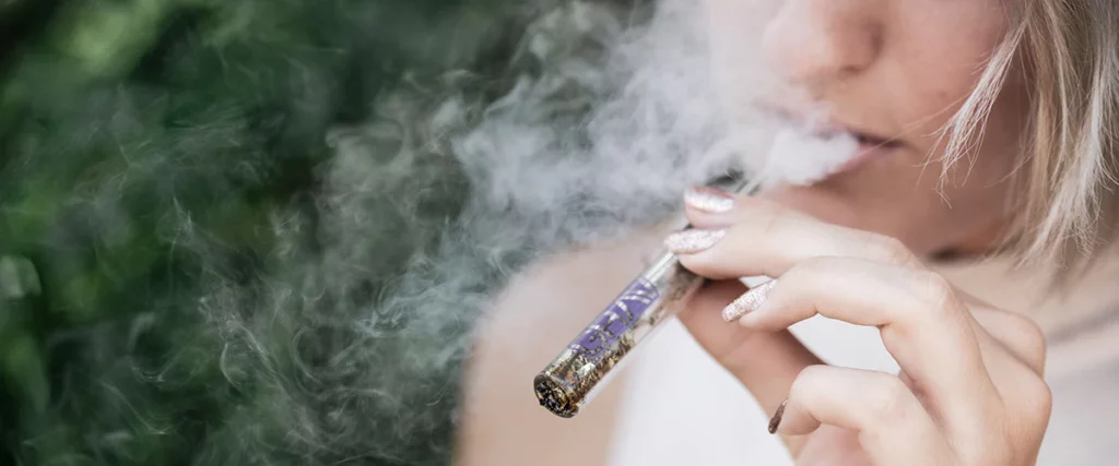 woman exhaling smoke after inhaling a cannabis vaporizer