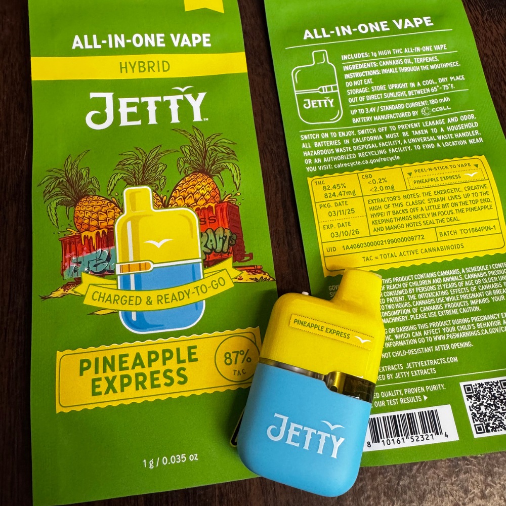 2 lime green empty packages of Jetty Extracts Pineapple Express all in one mini are on the table with the vape cart sticker on the device.