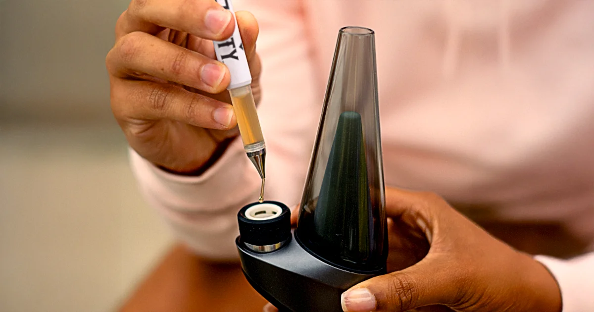Person using a Jetty Extracts Dablicator to dispense a drop of cannabis oil into a Puffco Peak portable dab device, demonstrating precise dosing for vaporization