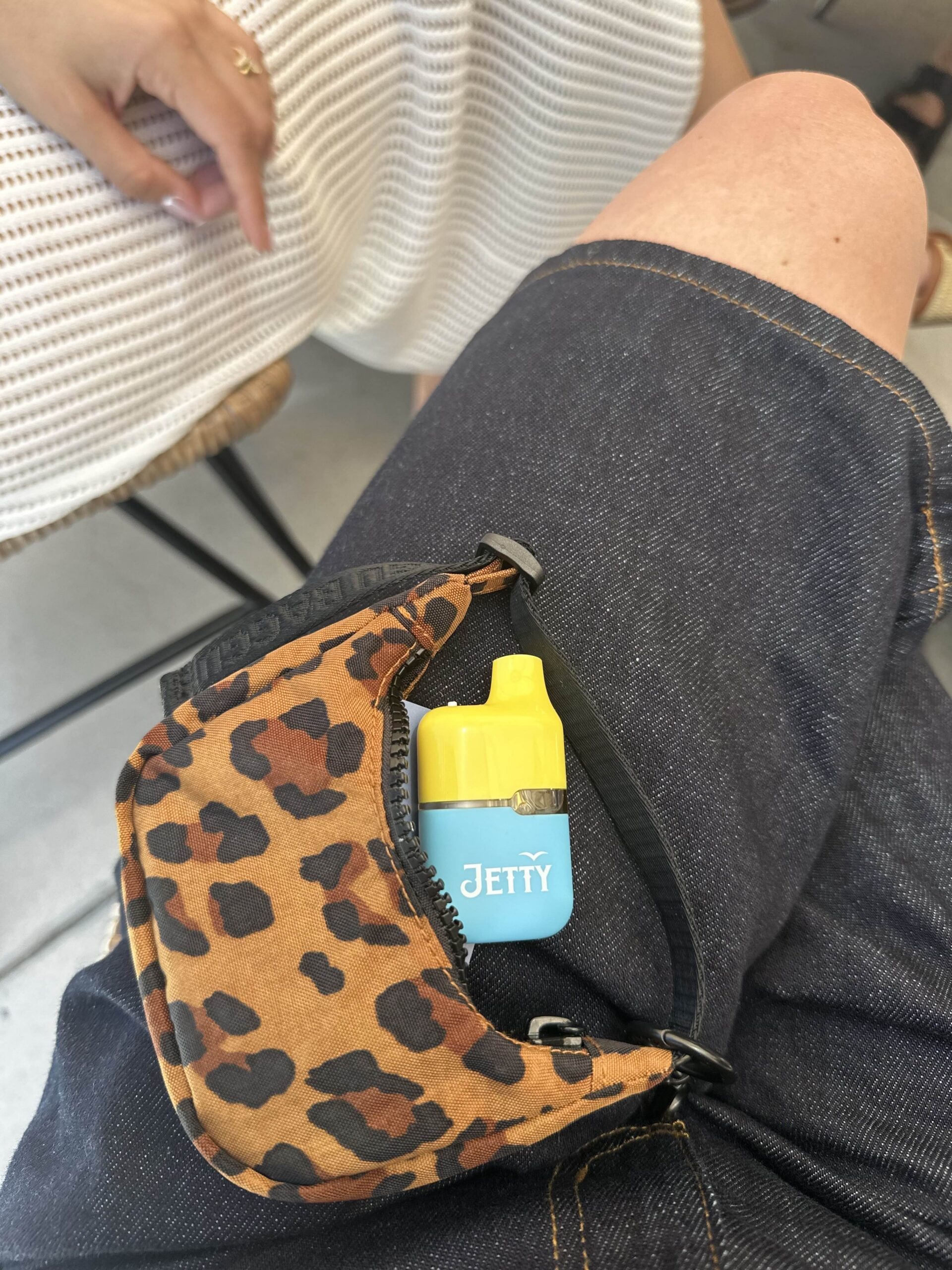 Jetty High THC Mega Tank tucked into a leopard-print bag on a person’s lap.